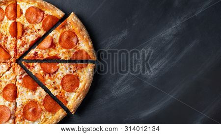 Tasty Pepperoni Pizza And Cooking Ingredients Tomatoes Basil On Black Concrete Background. Top View 