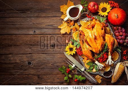 Thanksgiving dinner. Roasted turkey with pumpkins and sunflowers on wooden table