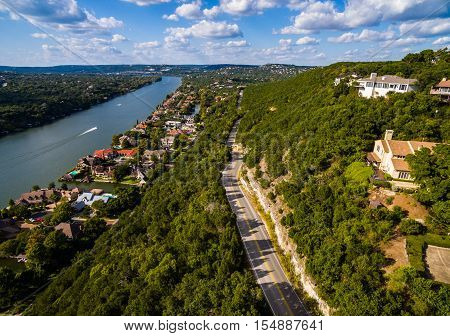 Texas Hill Country Mount Bonnell Road to Texas Texas Hill Country,  Mount Bonnell. Road to Texas aerial Shot over Austin , Texas. Windy road and Houses along the Colorado River or Town Lake with boats driving across the water. The Blue Sky was partly clou