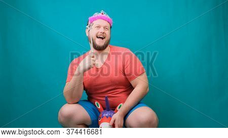 A Youna Young Bearded Freaky Man In A Pink T-shirt With A Diadem On His Head Riding A Unicorn With A