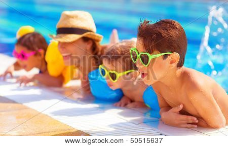 Happy family in the pool, having fun in the water, mother with three kids enjoying aquapark, beach resort, summer holidays, pleasure concept 