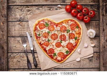 Vegetarian heart shaped pizza margherita with tomatoes, mozzarella, parsley and garlic on vintage wo