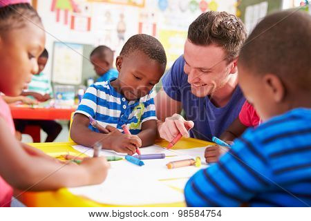 Volunteer teacher helping a class of preschool kids drawing