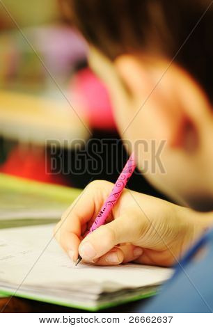 Kid in classroom with pen in hand