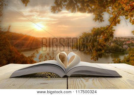 Open book at wooden table on natural blurred background. Heart books page. Back to school. Copy Spac