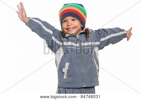 Happy mixed race little girl wearing a colorful beanie hat offering a hug with wide open arms isolated on white