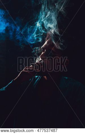 Black Young Man With Glasses Smoking Cigar With Fog At Black Background