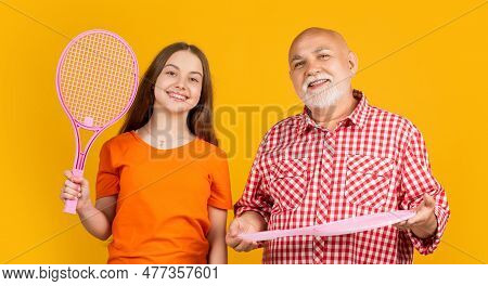 Happy Teen Child With Grandfather With Badminton Racket On Yellow Background