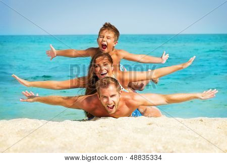 Happy Young Family with Little Kid Having Fun at the Beach. Joyful Family. Travel and Vacation