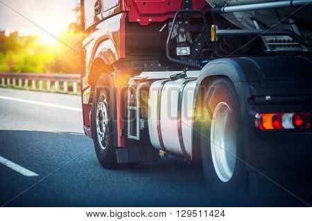 Red Semi Truck Speeding on a Highway. Tractor Closeup. Transportation and Logistics Theme.