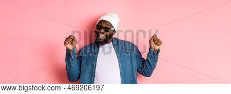 Happy And Carefree Black Man Celebrating, Dancing And Having Fun, Wearing Beanie And Sunglasses, Sta