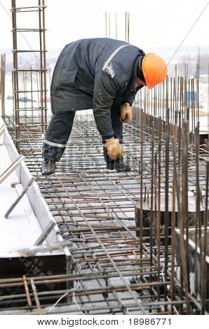 worker in workwear making reinforcement metal framework for concrete pouring