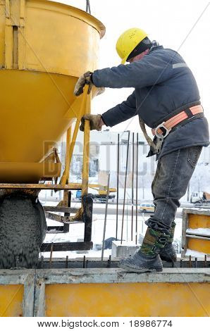 construction building worker at construction site pouring concrete in mould