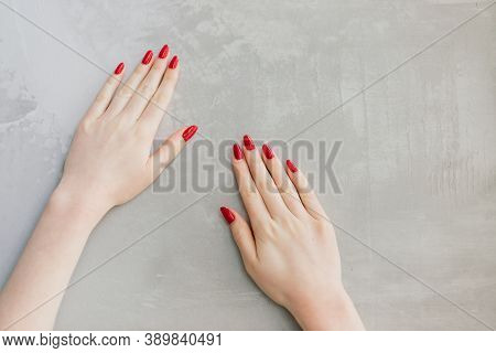 Isolated Woman's Hands With Red Nails In Front Of Grey Wall