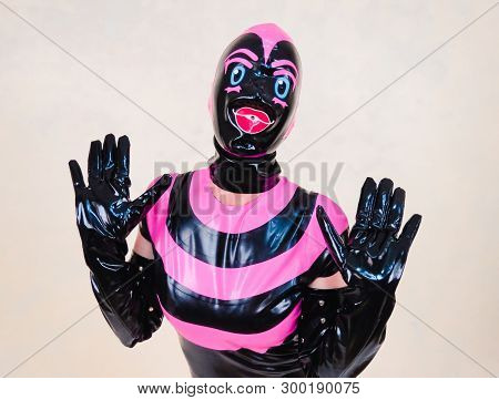 Hooded Woman Holding Up Gloved Hands In Expression Of Shock Or Surprise. Pink And Black Rubber Latex