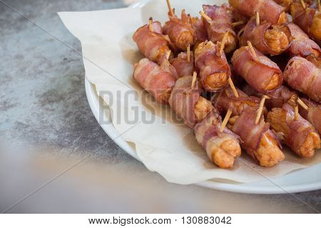 Deep fried sausages rolled in bacon on wood background