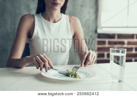 Woman Sitting On Chair And Eating Salad On Plate. Diet Concept. Weight Loss Problem. Starving Young 