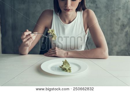 Woman Sitting On Chair And Eating Salad On Plate. Diet Concept. Weight Loss Problem. Starving Young 