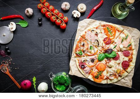 Food frame with italian pizza, ingredients, vegetables and spices on dark background. Flat lay, top view. Food background