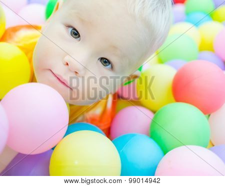 Cute kid boy playing with colorful balls 