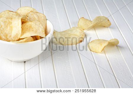 Delicious Golden Potato Chips In A White Bowl On A White Wooden Background. Food Background.