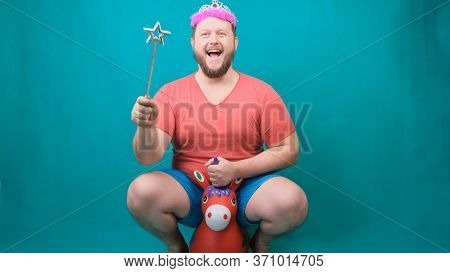 A Youna Young Bearded Freaky Man In A Pink T-shirt With A Diadem On His Head Riding A Unicorn With A