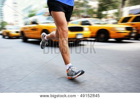 Running in New York City - man city runner jogging in street of Manhattan with yellow taxi caps cars and traffic. Urban lifestyle image of male jogger training downtown. Legs and running shoes.