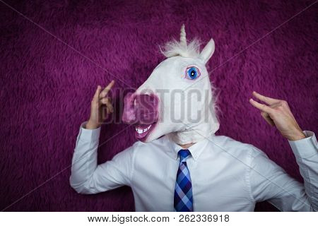 Freaky Young Man In Comical Mask Stands On The Purple Background. Portrait Of Unusual Manager. Funny