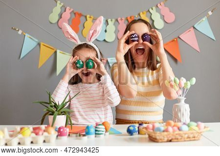 Happy Easter. Image Of Surprised Funny Mother And Her Daughter Covering Eyes With Easter Eggs And Sc