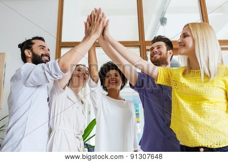 business, startup, gesture, people and teamwork concept - happy creative team making high five in office