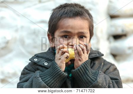 MUKTINAH, NEPAL, NOVEMBER 10, 2010 : Poverty in Nepal, a starving kid is eating an apple  in the small mountain village of Muktinah, Annapurna, Nepal.