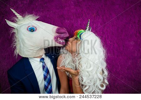 Portrait Of Unusual Couple On The Purple Background. Freaky Young Woman In Unusual Wig And Red Dress