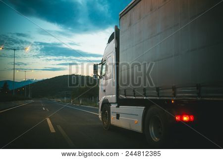 Lorry Car Drive On Road In Evening. Truck Transport Cargo. Transportation And Shipment. Speed And De