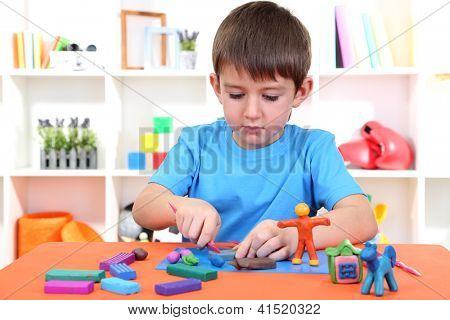 Cute little boy moulds from plasticine on table