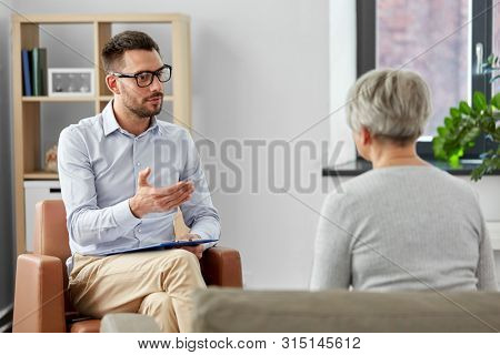 geriatric psychology, mental therapy and old age concept - psychologist talking to senior woman patient at psychotherapy session