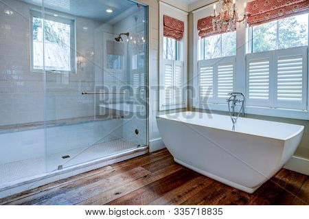 Beautiful luxury bathroom with large white tub and white tile walk in shower.