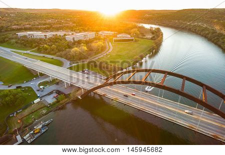 Sunset Sunrays Aerial Above Pennybacker Bridge or 360 Bridge or Capital of Texas highway Bridge Austin Texas cars driving across the Colorado River as Boat passing under the Suspension Bridge