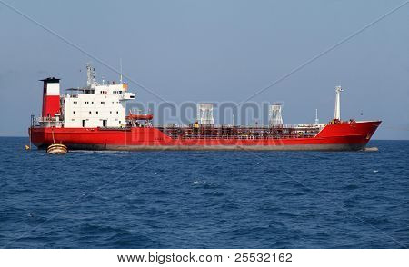 Red tanker designed for transporting crude oil is at anchor near the port