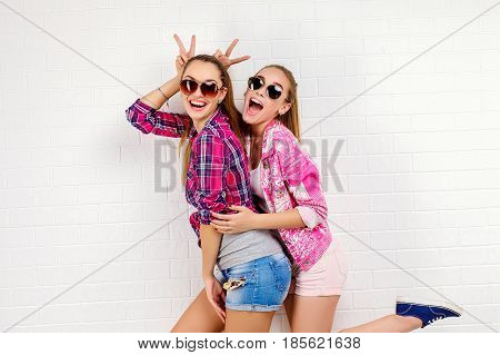 Fashion portrait of two friends posing. modern lifestyle.two stylish sexy hipster girls best friends ready for party.Two young girl friends standing together and having fun. Looking at camera.