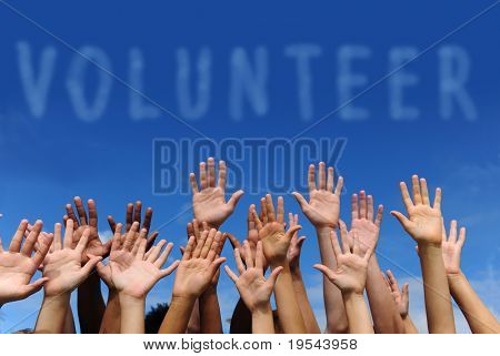 volunteer group raising hands against blue sky background