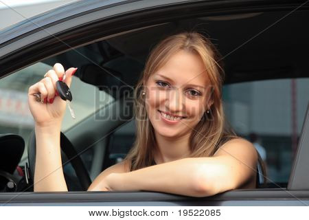 The happy woman showing the key of her new car