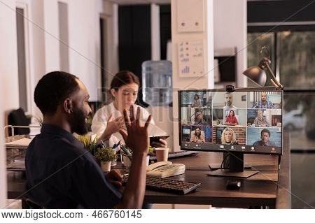 African American Man Talking With Colleagues On Online Group Chat, Greeting Coworkers, Waving Hi. Of