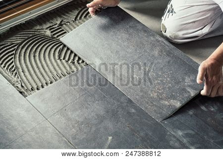 Worker`s Hands Placing Ceramic Floor Tile With Precision On Adhesive Surface