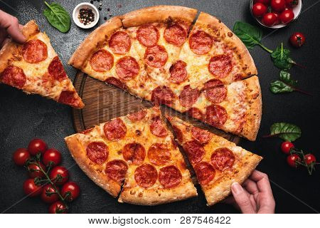 Picking Slice Of Pepperoni Pizza. Hands Picking Pizza Slice. Top View Of Tasty Hot Pepperoni Pizza O