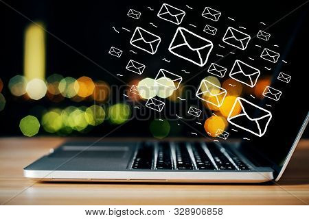 Side View Of Laptop On Desktop With Digital Emails On Bokeh Background. E-mail Network And Marketing