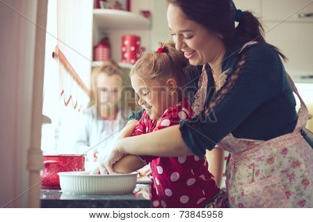 Mother with her 5 years old kids cooking holiday pie in the kitchen to Mothers day, casual lifestyle photo series in real life interior