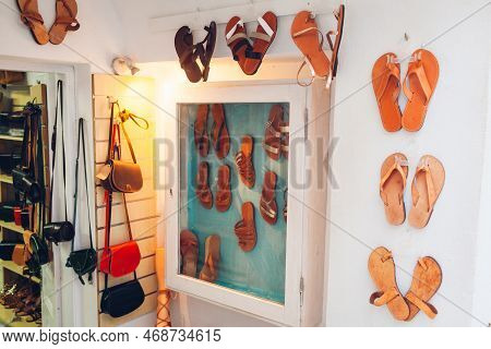 Display Of Shoes Store. Summer Sandals And Handbags Hanging On Wall. Leather Handmade Flats In Retro