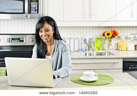 Mulher usando o computador na cozinha